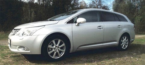 En silverfärgad Nissan Avensis parkerad på en åker. (AI text)