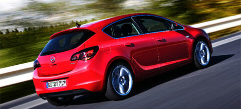 En röd Opel Astra kör nedför en väg. (AI text)