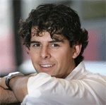 En man med krulligt hår lutar sig mot en vägg. (AI text)