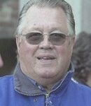 En man i en blå jacka och solglasögon. (AI text)