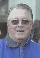 En man i en blå jacka och solglasögon. (AI text)