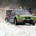 En rallybil kör genom snön. (AI text)
