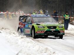 En rallybil kör genom snön. (AI text)