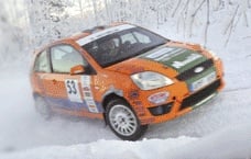 En Ford Fiesta rallybil kör genom snön. (AI text)