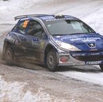 En rallybil körer nedför en snöig väg. (AI text)