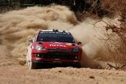 En rallybil kör genom en dammig omgivning. (AI text)