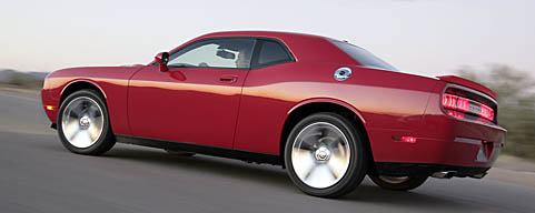 En röd Dodge Challenger SXT kör ner en väg. (AI text)