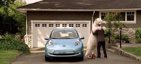 En man och en kvinna står framför en Nissan Leaf. (AI text)