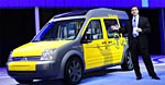 En man i kostym står bredvid en gul minibuss. (AI text)