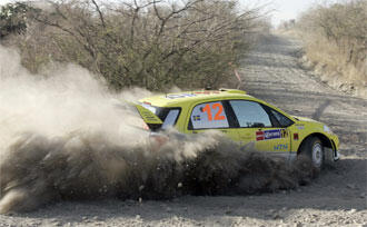 En gul rallybil kör genom en stämd jordväg. (AI text)