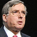 En man i kostym och slips talar. (AI text)