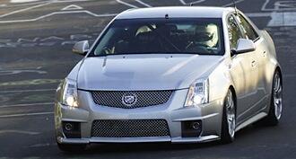 En silverfärgad Cadillac CTS kör ner en gata. (AI text)
