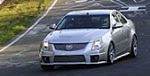 En silverfärgad Cadillac CTS kör nerför en backe. (AI text)