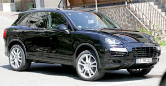 En svart Porsche Cayenne parkerad på en gata. (AI text)