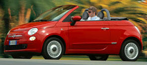 En röd Fiat 124 cabriolet kör nedför en väg. (AI text)