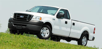 En vit lastbil parkerad på en gräsmatta. (AI text)