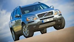 En Volvo XC90 SUV kör på en grusväg. (AI text)
