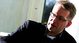 En man med glasögon spelar gitarr. (AI text)