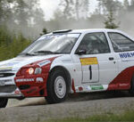 En rallybil körer längs en grusväg. (AI text)