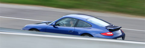 En blå Porsche 911 tävlar på en racerbana. (AI text)