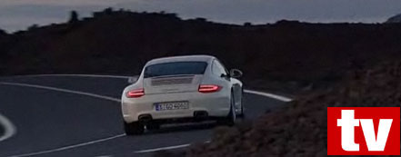 En vit Porsche 911 GTS kör nedför en bergsväg. (AI text)