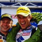 En motorsportförare höjer upp en pokal. (AI text)
