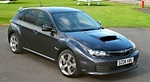 En svart Subaru WRX STI parkerad på en parkeringsplats. (AI text)