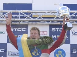 En racerkörare höjer upp sin pokal. (AI text)