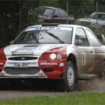 En rallybil kör på en grusväg. (AI text)