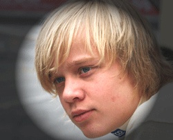 En ung man med blont hår och kostym. (AI text)