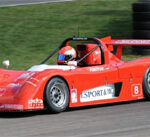 En röd racerbil kör nedför banan. (AI text)