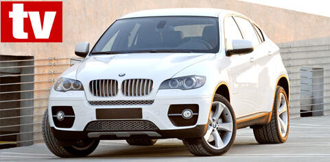 En BMW X6 SUV parkerad framför ett byggnad. (AI text)