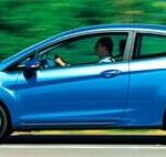 En blå Ford Fiesta kör nedför en väg. (AI text)