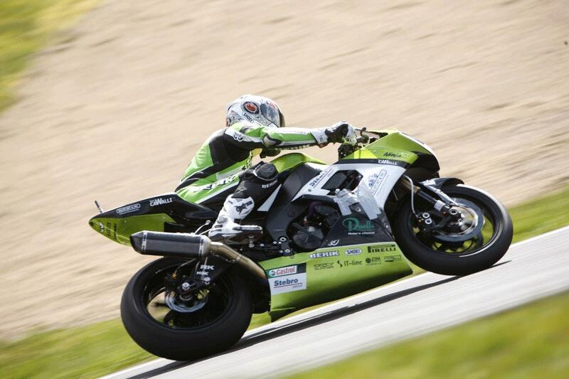 En grön motorcykel rasar nedför en backe. (AI text)