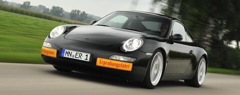 En svart Porsche 911 kör nedför en landsväg. (AI text)