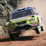 En rallybil kör nerför en grusväg. (AI text)