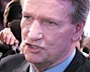 En man i kostym och slips pratar med journalister. (AI text)