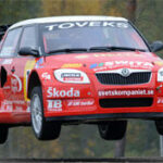 En röd Skoda Rallybil i luften. (AI text)