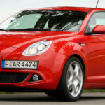 En röd Alfa Romeo kör nedför en väg. (AI text)