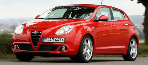 En röd Alfa Romeo kör nedför en väg. (AI text)