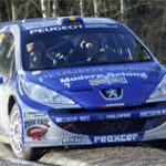 En rallybil kör på en snöig väg. (AI text)