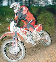 En person cyklar en dirtbike på en grusväg. (AI text)