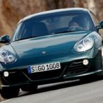 En gröngul Porsche Cayman kör nedför en bergsväg. (AI text)