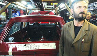 En man står bredvid en bil i en fabrik. (AI text)