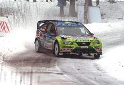 En rallybil kör nerför en snöig väg. (AI text)