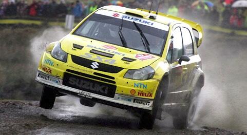 En rallybil kör genom en blöt och smutsvåt yta. (AI text)