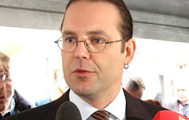 En man i kostym och slips pratar med journalister. (AI text)