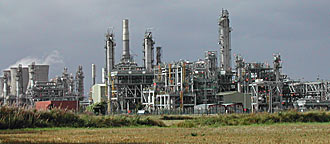 En stor oljeanläggning med ett stort fält i bakgrunden. (AI text)