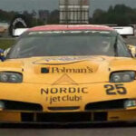 En gul Chevrolet Corvette C6-racebil kör nedför en racebana. (AI text)