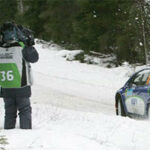 En rallybil kör nedför en snöig väg. (AI text)